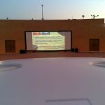 MovieMovil, la empresa de cine al aire libre, transforma los parques de Ibi en escenarios cinematográficos Proyección de cine al aire libre en un parque de Ibi, con una gran pantalla mostrando información sobre MovieMovil, incluyendo servicios como proyecciones de películas, documentales, deportes y videojuegos. El entorno incluye árboles y un espacio abierto que crea un ambiente relajado y natural. MovieMovil, la empresa de cine al aire libre