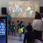 MovieMovil, la empresa de cine al aire libre, añade diversión con proyecciones animadas en fiestas infantiles Proyección sobre la pared en una fiesta infantil con animación colorida mientras los niños disfrutan sentados y observan la pantalla. MovieMovil, la empresa de cine al aire libre