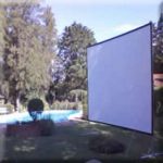 MovieMovil, la empresa de cine al aire libre, crea experiencias únicas en jardines y espacios verdes Proyección de cine al aire libre junto a una piscina en un jardín, con una gran pantalla blanca, rodeada de árboles y arbustos que crean una atmósfera tranquila y agradable. MovieMovil, la empresa de cine al aire libre